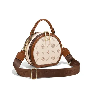 Detail of white printed crossbody bag with brown trim and wide logo fabric strap