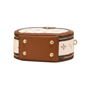 Detail view of the brown cylinder bag base with protective metal feet and leather texture