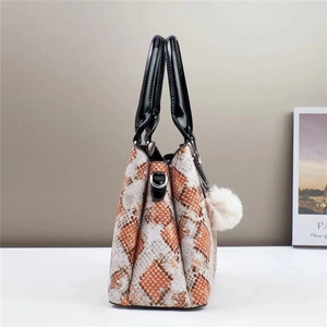 Textured faux snake skin tote bag in orange and brown with a white plush pompom charm
