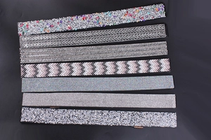 Detail verschiedener Strass-Elastikgürtel mit silbernen Glitzertexturen auf Schwarz
