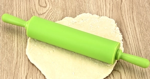 Close-up of a 30.5cm green non-stick silicone rolling pin on dough and wood background