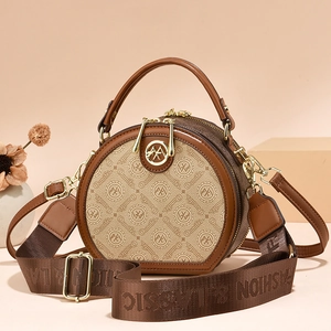 Brown and beige patterned round crossbody bag with leather handles and wide logo strap
