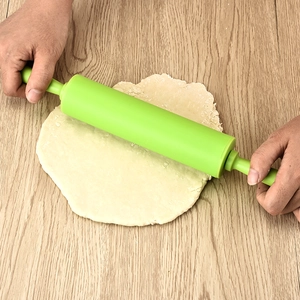 30.5cm green non-stick silicone rolling pin flattening dough on a wooden table