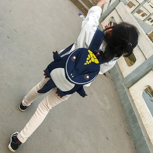 Close-up of navy blue dinosaur backpack featuring yellow fins and adjustable straps