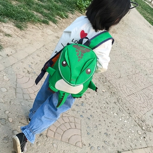 Rear view of a child wearing a green dinosaur backpack on a park trail during hiking