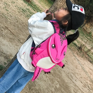 Outdoor view of a pink 3D dinosaur backpack for kids with scales and long tail