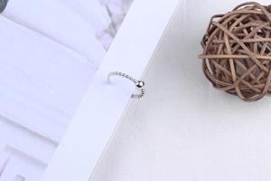 Close-up of minimalist silver beaded ring on a white book page with natural lighting