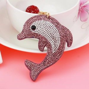 Detail of pink and white rhinestone dolphin keychain with gold metal ring on cup edge