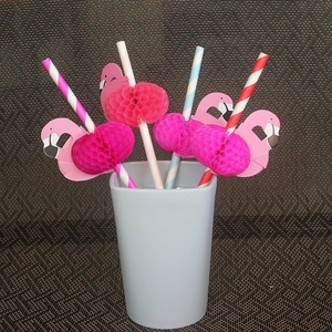 Detail of pink flamingo honeycomb decorations on colorful striped paper straws in a cup