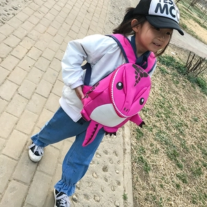 Pink cartoon dinosaur backpack for kids with 3D tail and feet shown on small girl