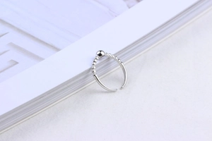 Detail of silver beaded open ring on a magazine showing minimalist design and metal texture