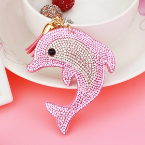 Detail of dolphin bag charm featuring pink rhinestones, golden metal ring and soft tassel