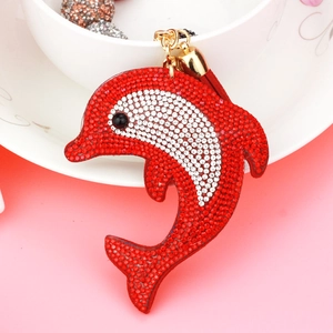 Detail of dolphin bag charm with red and white rhinestones, gold buckle and red tassel