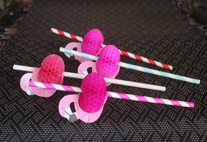 Detail of flamingo paper straws with pink honeycomb decorations and colorful stripes