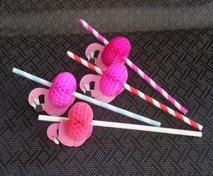 Detail showing five striped paper straws with pink flamingo honeycomb decorations on a mat