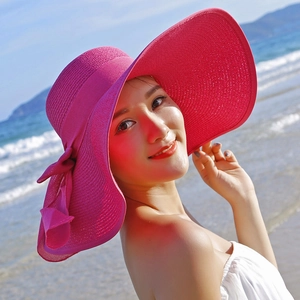 Rose red wide brim straw sun hat with bow detail against a tropical beach backdrop