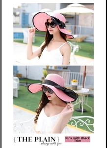 Detalle de sombrero de paja rosa con lazo negro y ala ancha para vacaciones en playa