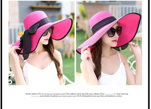 Detalle de sombrero de paja fucsia de ala ancha con lazo negro para protección solar playa