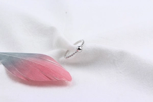 Macro shot of 925 sterling silver beaded ring with large bead detail on white fabric