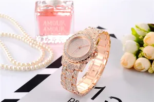 Primo piano dell'orologio in oro rosa con diamanti accanto a un flacone di profumo