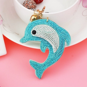 Macro detail of dolphin bag charm with blue and white rhinestones and gold hardware