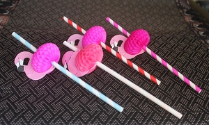 Detailed view of pink honeycomb flamingo ornaments on colorful striped paper straws