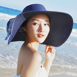 Navy blue wide brim straw sun hat for women featured in a scenic beach holiday setting