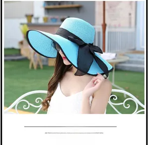 Detailaufnahme einer Frau mit einem blauen Sonnenhut aus Stroh und schwarzer Schleife