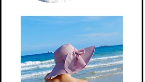 Primer plano de sombrero de paja lavanda con lazo grande y ala ancha en una playa soleada