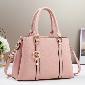 Detail of pink pebbled leather handbag with gold star pendant and adjustable strap