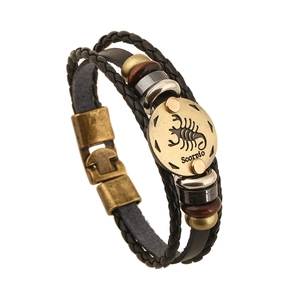 Detailed close-up of Scorpio zodiac leather bracelet with bronze charms and metal disc