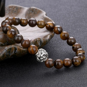 Macro shot of brown tiger eye stone beads and silver lion head charm on black stone
