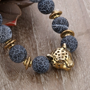 8mm black weathered agate beaded bracelet featuring a golden leopard head charm on wood