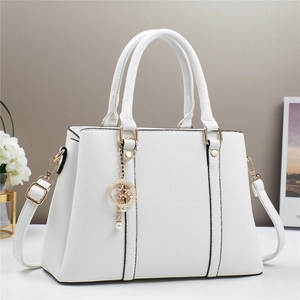 Close-up of white lychee leather texture and gold moon star charms on tote bag