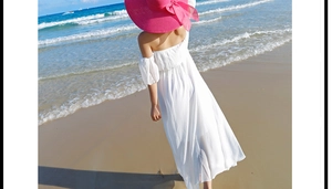 Vista trasera de mujer con vestido playero largo blanco de hombros caídos y espalda al aire