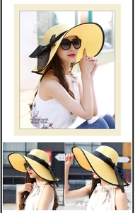 Detalle de sombrero de paja amarillo con borde negro y lazo grande decorativo