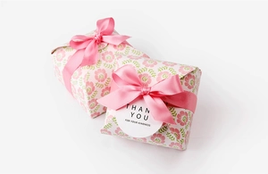 Detailed view of two gift boxes with pink floral patterns and elegant silk ribbon bows