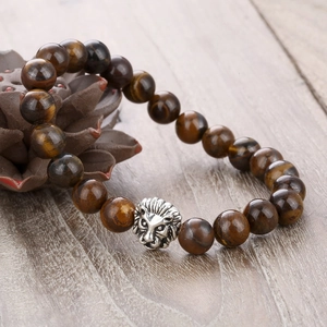 8mm tiger eye stone beaded bracelet featuring a silver lion head charm on a wooden surface
