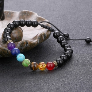 Close-up of a 7 chakra braided bracelet with matte black beads and adjustable drawstrings