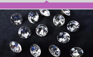 Macro shot of loose sparkling round-cut rhinestones on a textured blue fabric surface