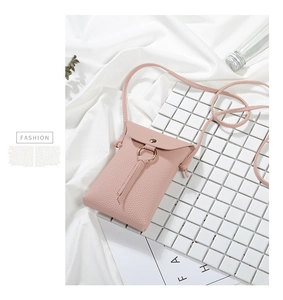 Dettaglio di una mini borsa a tracolla rosa in pelle martellata con fibbia dorata.