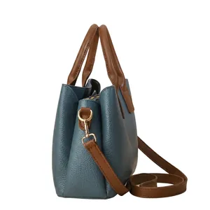 Dettaglio della borsa in pelle blu grigio con manici marroni e dettagli dorati