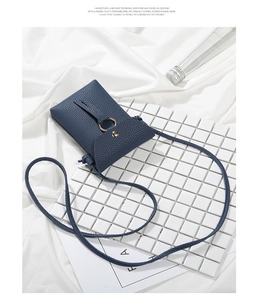 Detail view of navy blue lychee grain leather phone bag with gold ring buckle closure