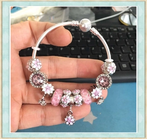 Detail of silver mesh bracelet with pink cherry blossom charms and sparkling crystals