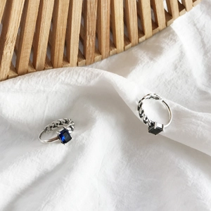 Macro detail of S925 sterling silver rings with black and blue stones on fabric