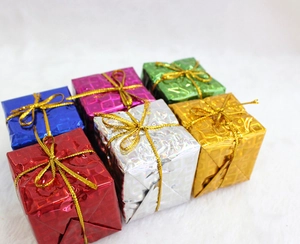 Close-up of colorful mini laser foil gift boxes with gold ribbons for Christmas trees