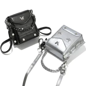 Detail view of mini phone bag featuring metallic butterfly decor and hexagon rivets