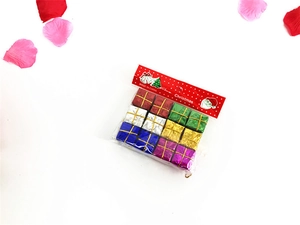 Close-up of 12 miniature colorful Christmas gift box ornaments on white background