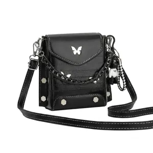 Detail of black crossbody bag with silver butterfly buckle and punk bear charm