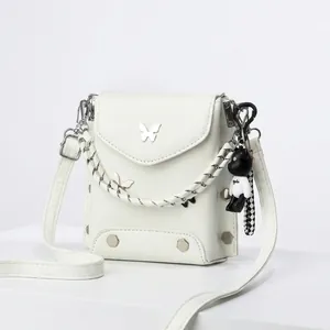 Detail view of small PU leather crossbody bag featuring silver butterfly logo and bear charm